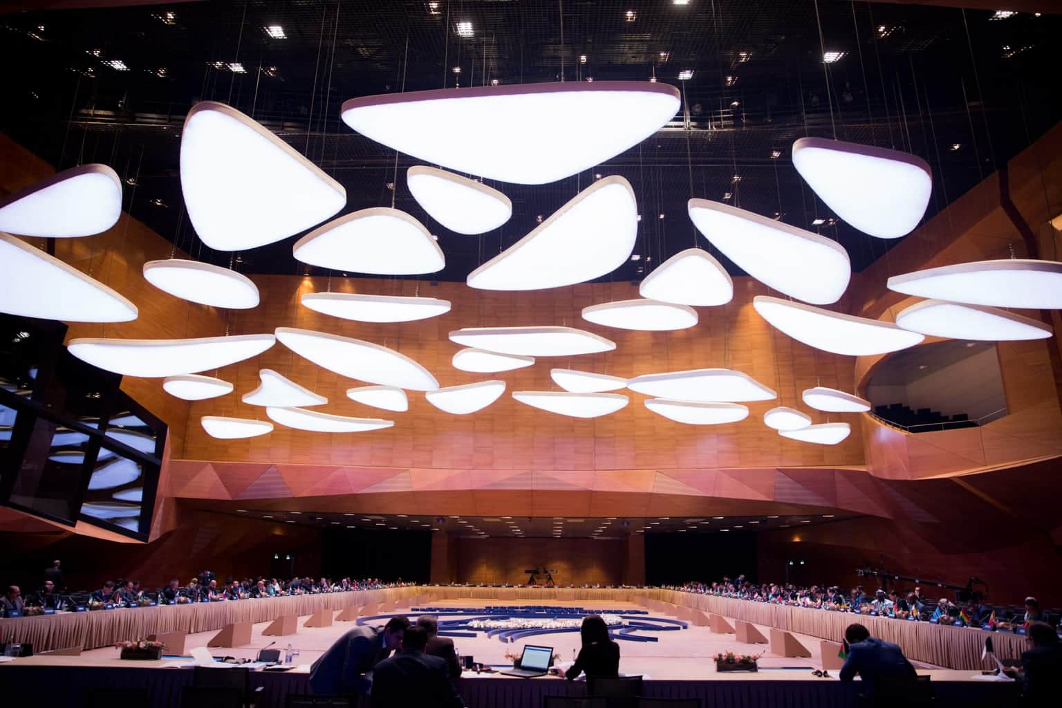 Delegates seated around the main-hall table at the Baku Convention Center beneath its suspended light panels