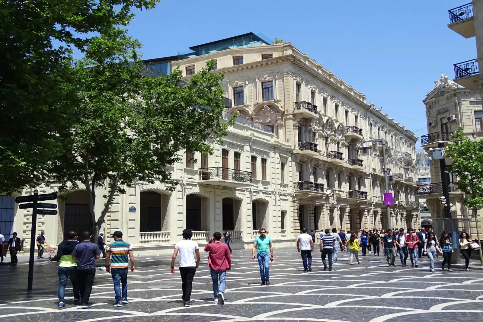 People walking past stone-fronted buildings near Fountain Square in central Baku