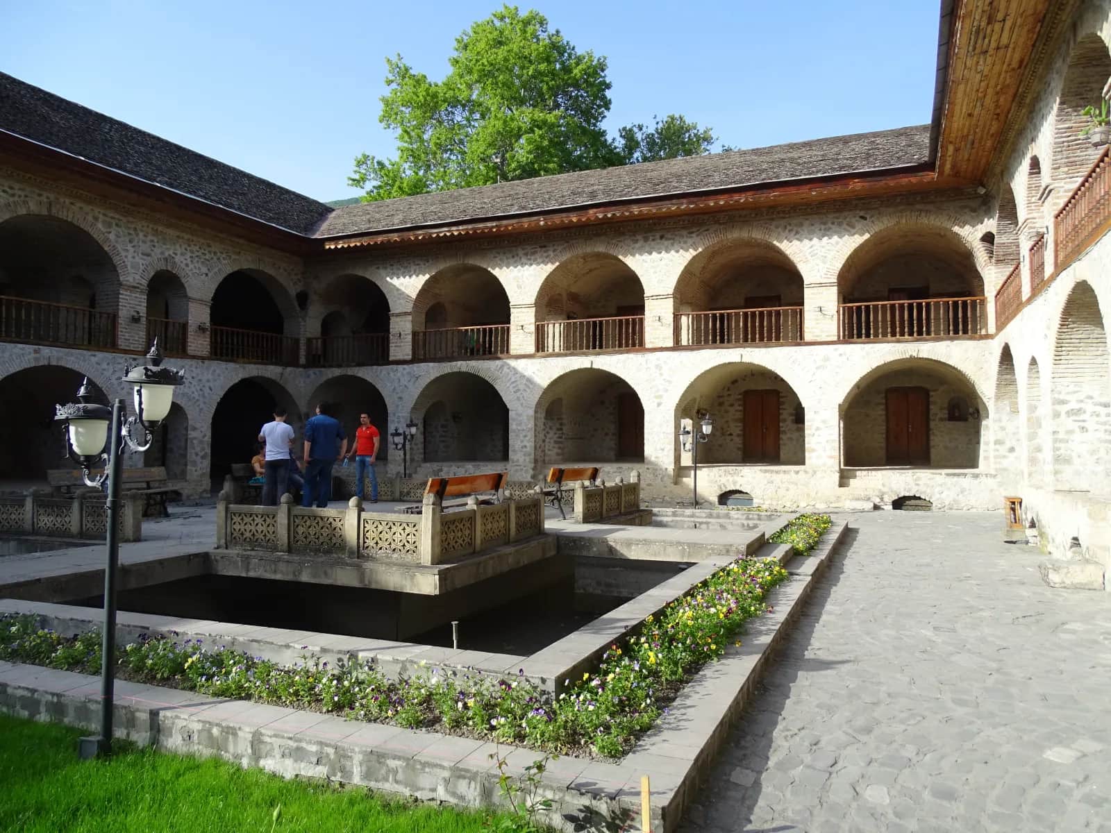 Stone arches and garden courtyard inside Sheki's historic Upper Caravanserai