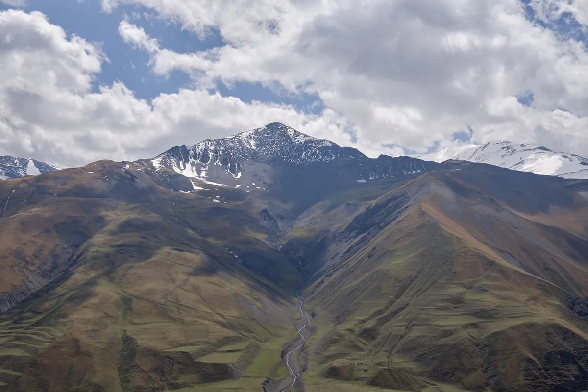 Snow-streaked mountain slopes and a river valley viewed from Khinalig in April 2023