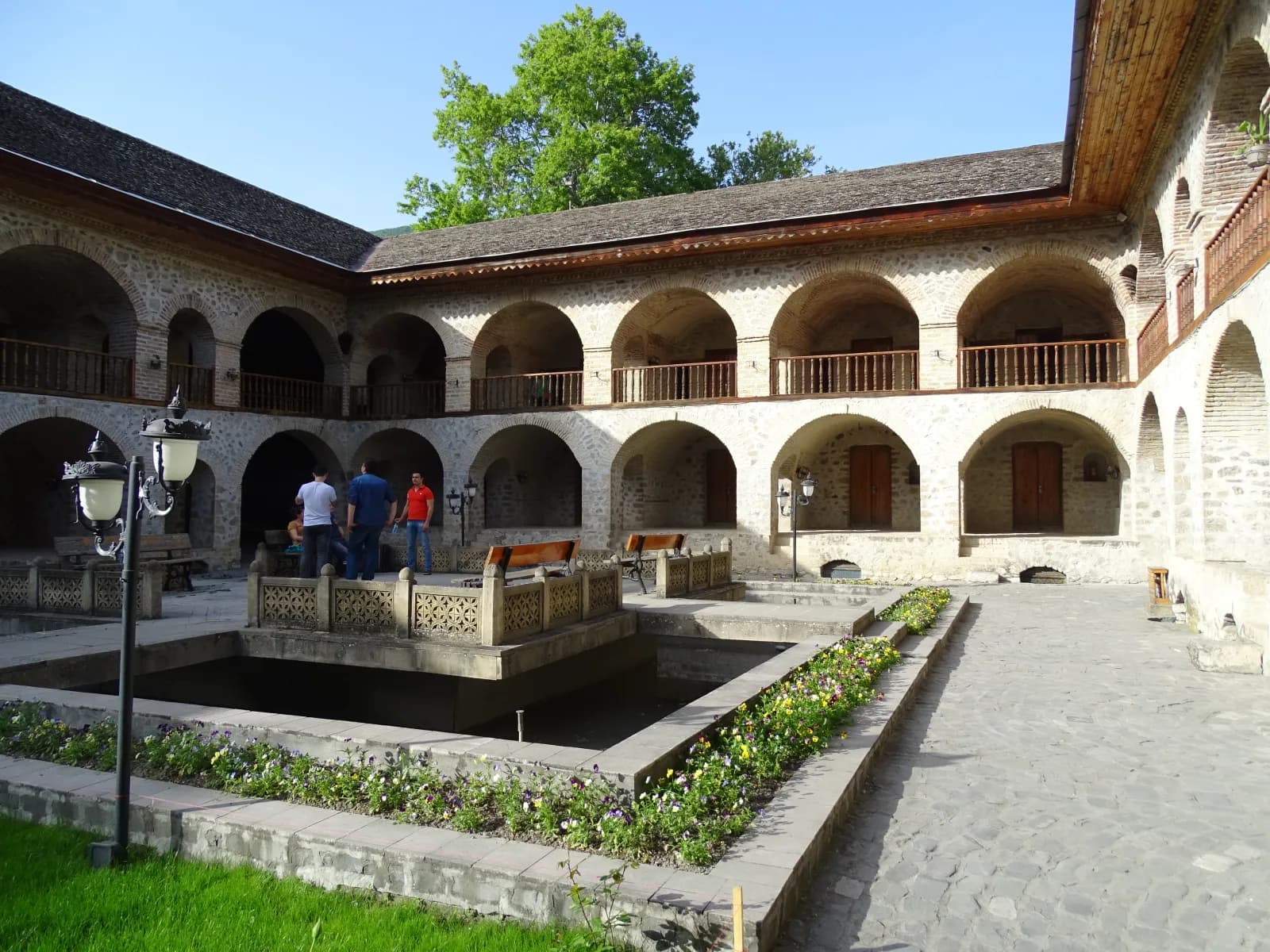 Stone arches and garden courtyard inside Sheki's historic Upper Caravanserai