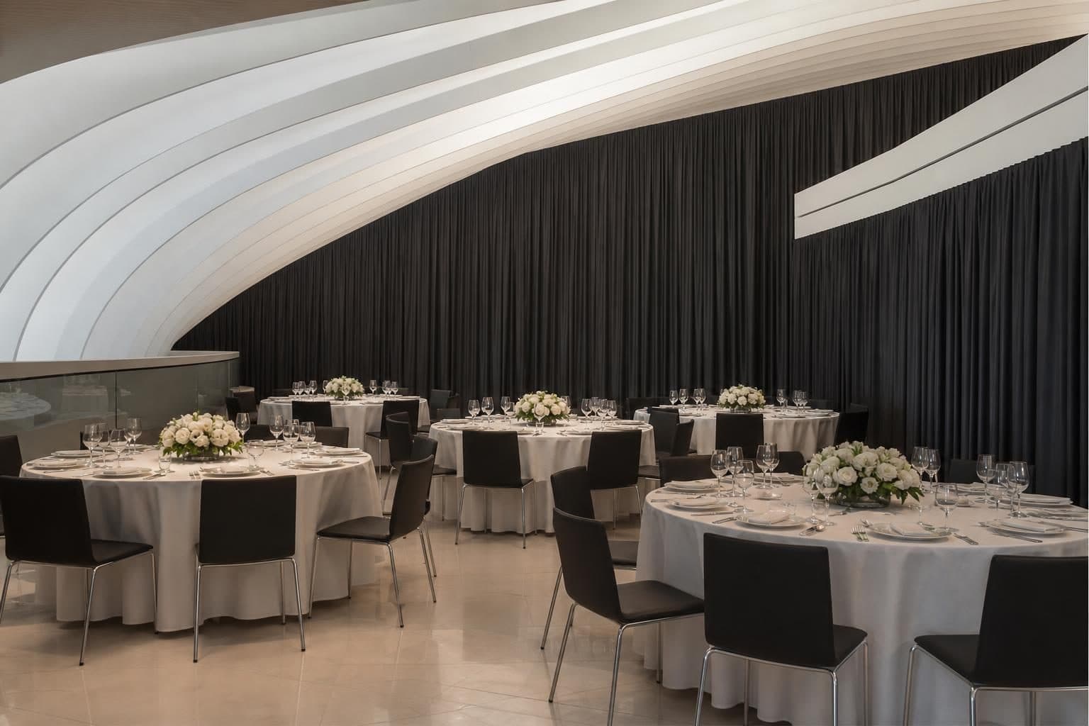6 round tables tightly clustered, white linens, low white florals, dark chairs, crystal glassware, Heydar Aliyev Center, Baku