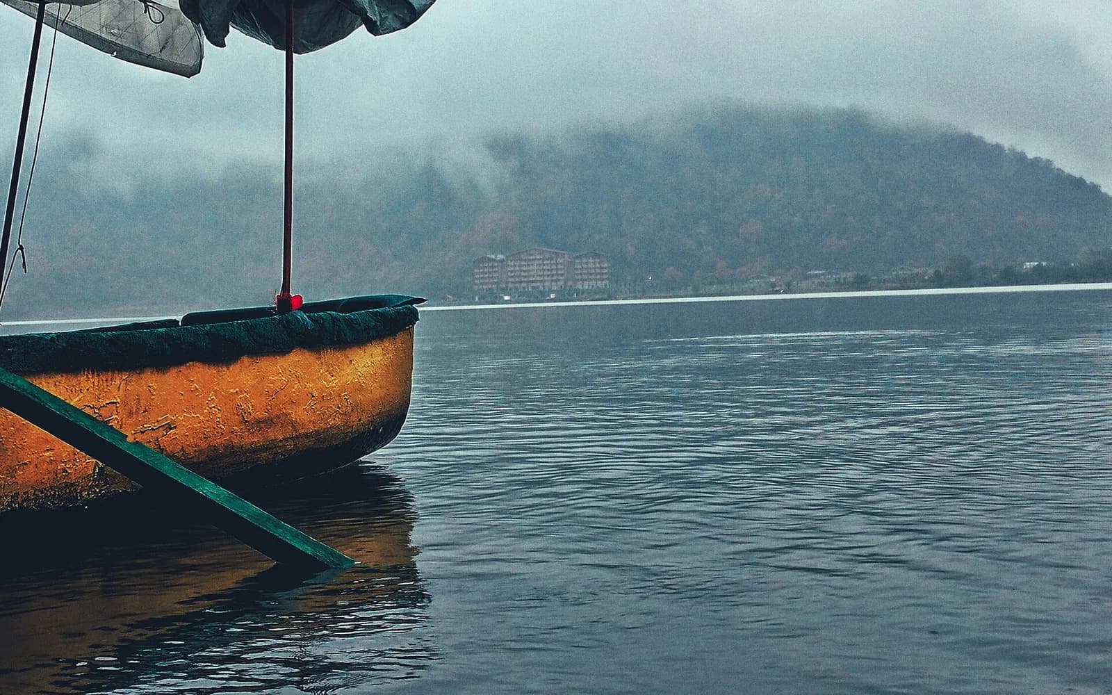 A boat on Nohur Lake beneath cloud-covered Gabala hills