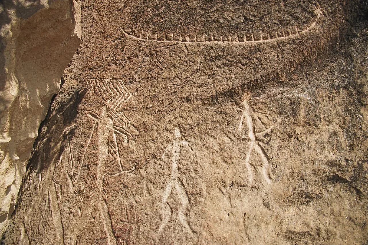 Human and animal figures engraved into a pale Gobustan rock face