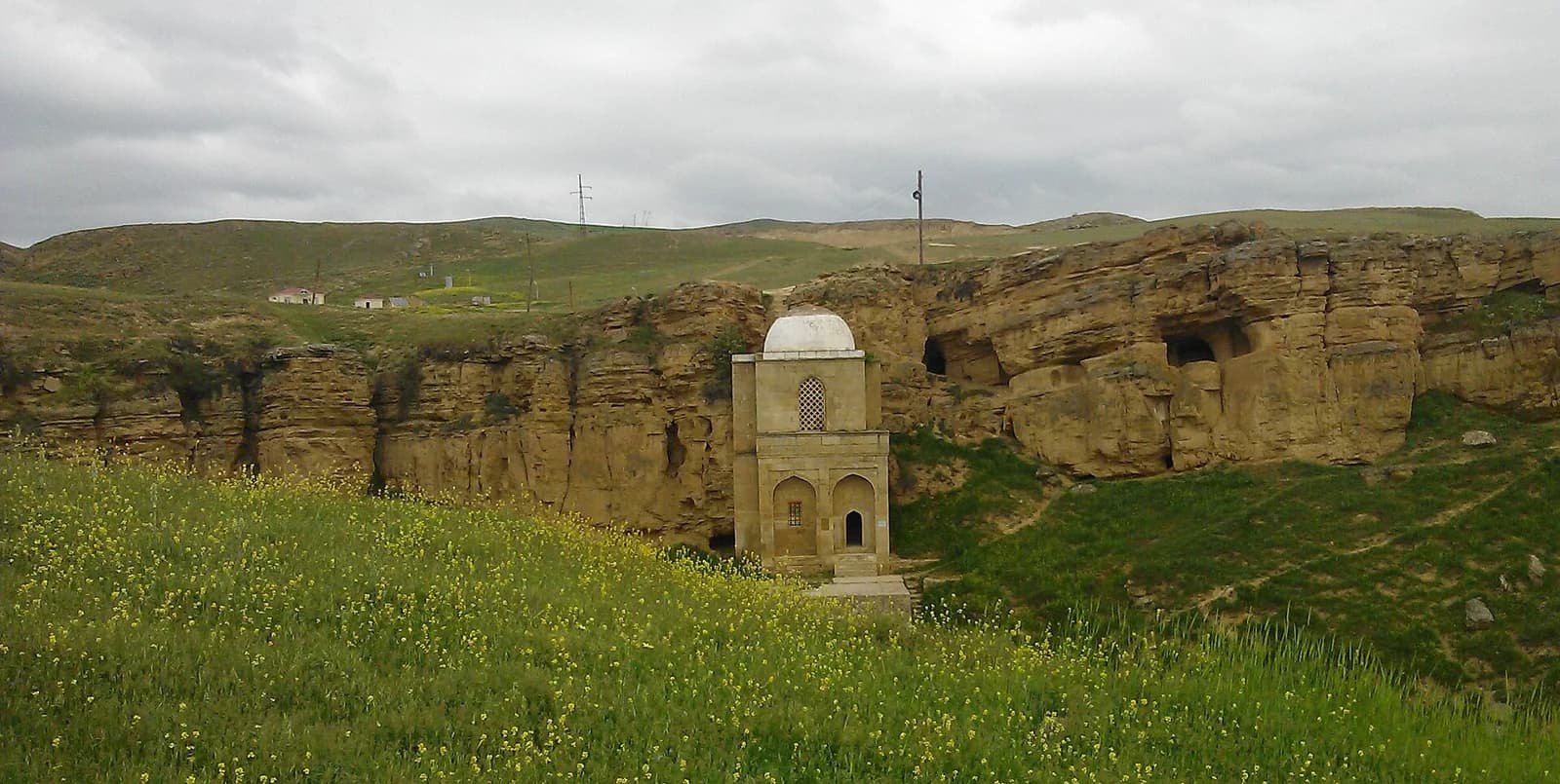 Diri Baba Mausoleum set against a rocky hillside and spring meadow
