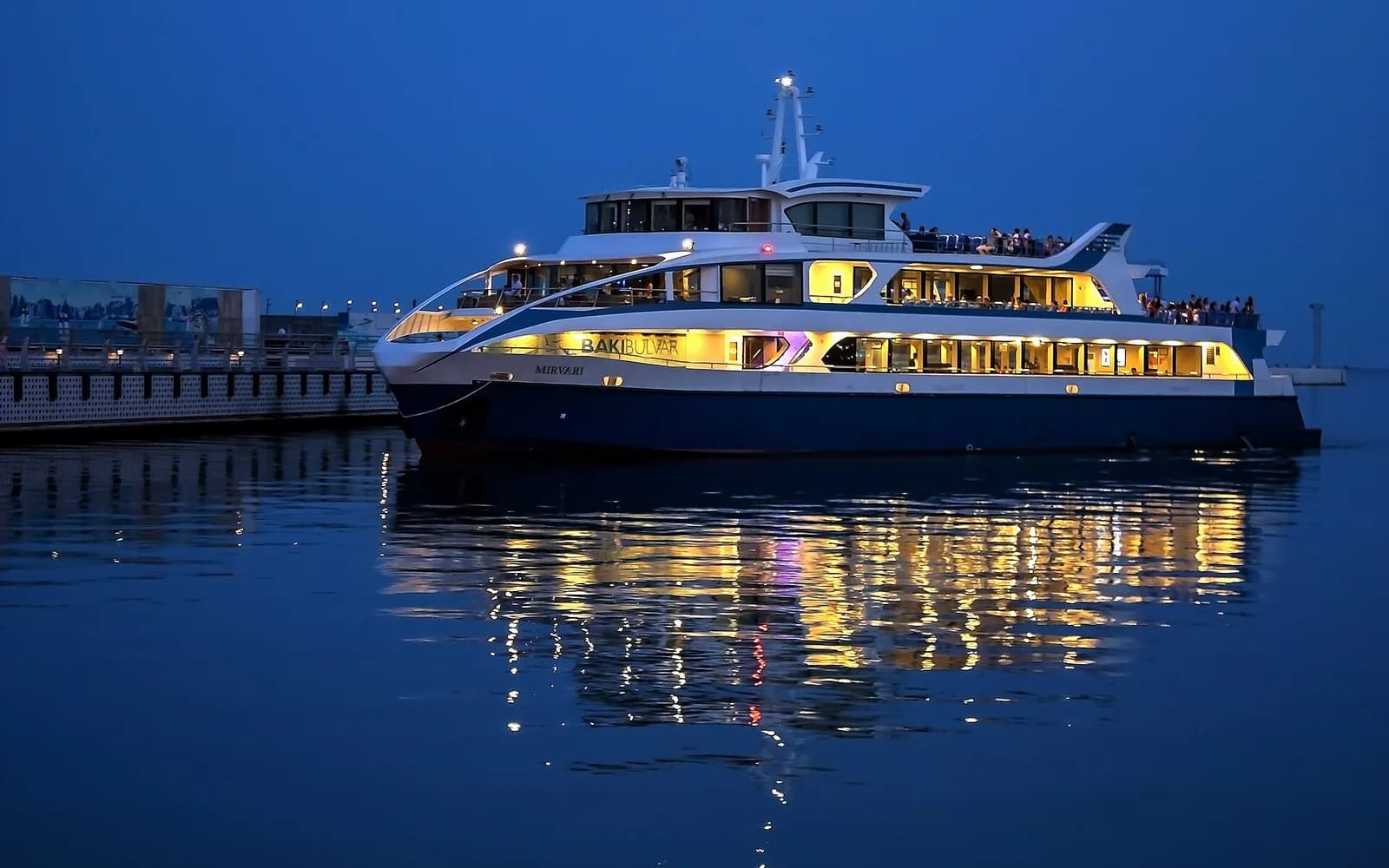 Illuminated pleasure boat on Baku Bay at dusk