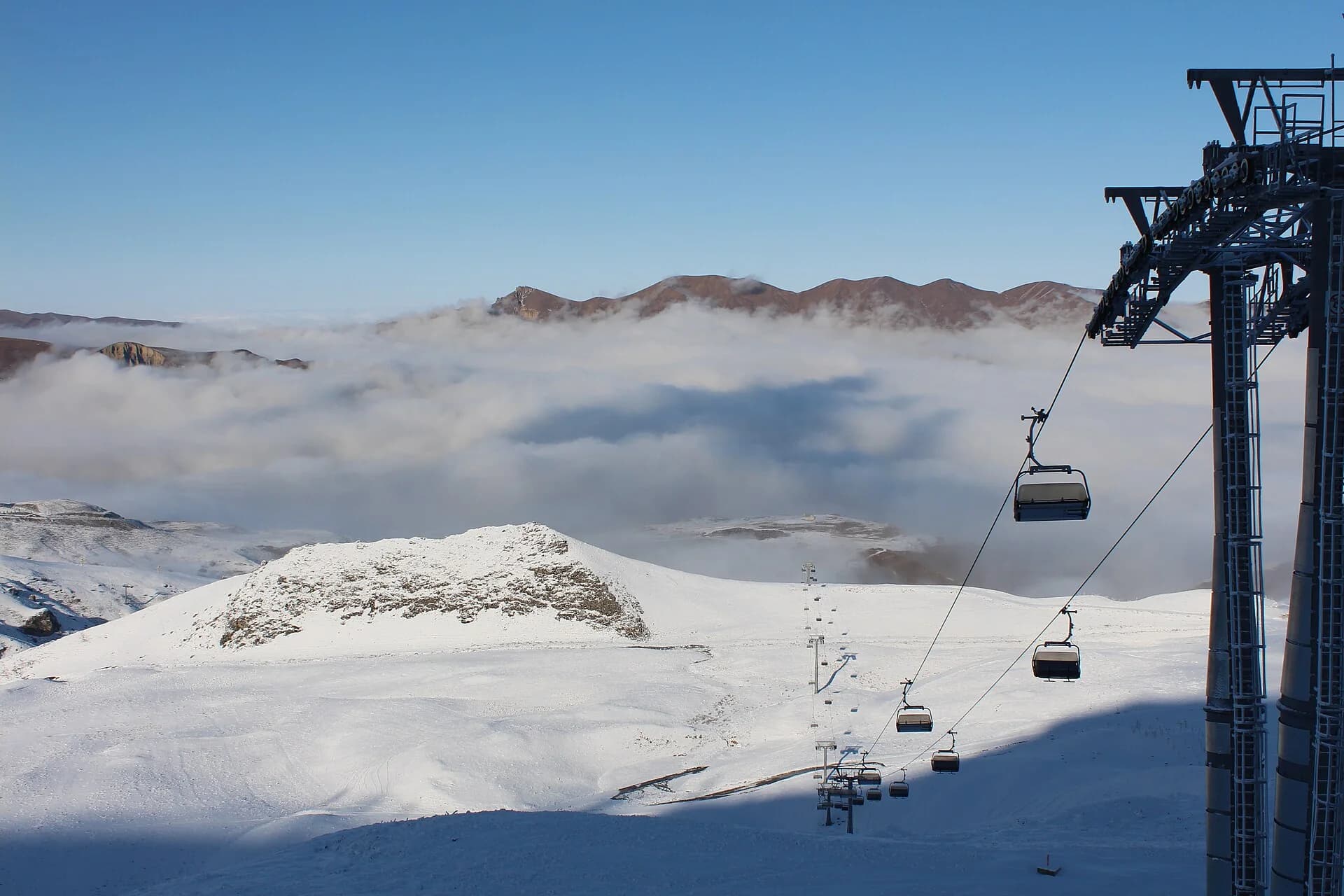 Chairlift over snowy slopes and clouds at Shahdag Mountain Resort