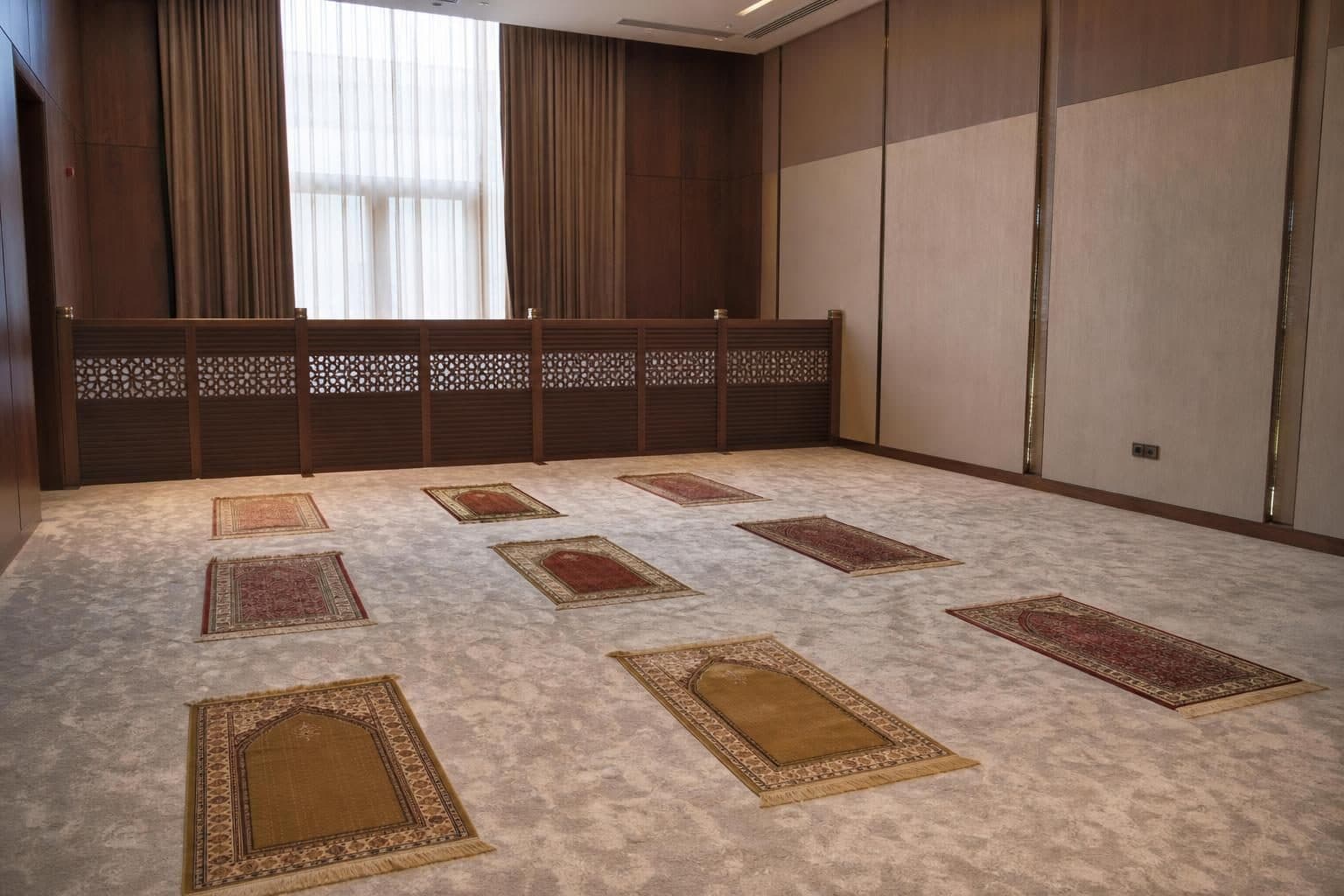 Soft neutral carpet, several individual prayer rugs in neat rows facing qibla direction, Baku