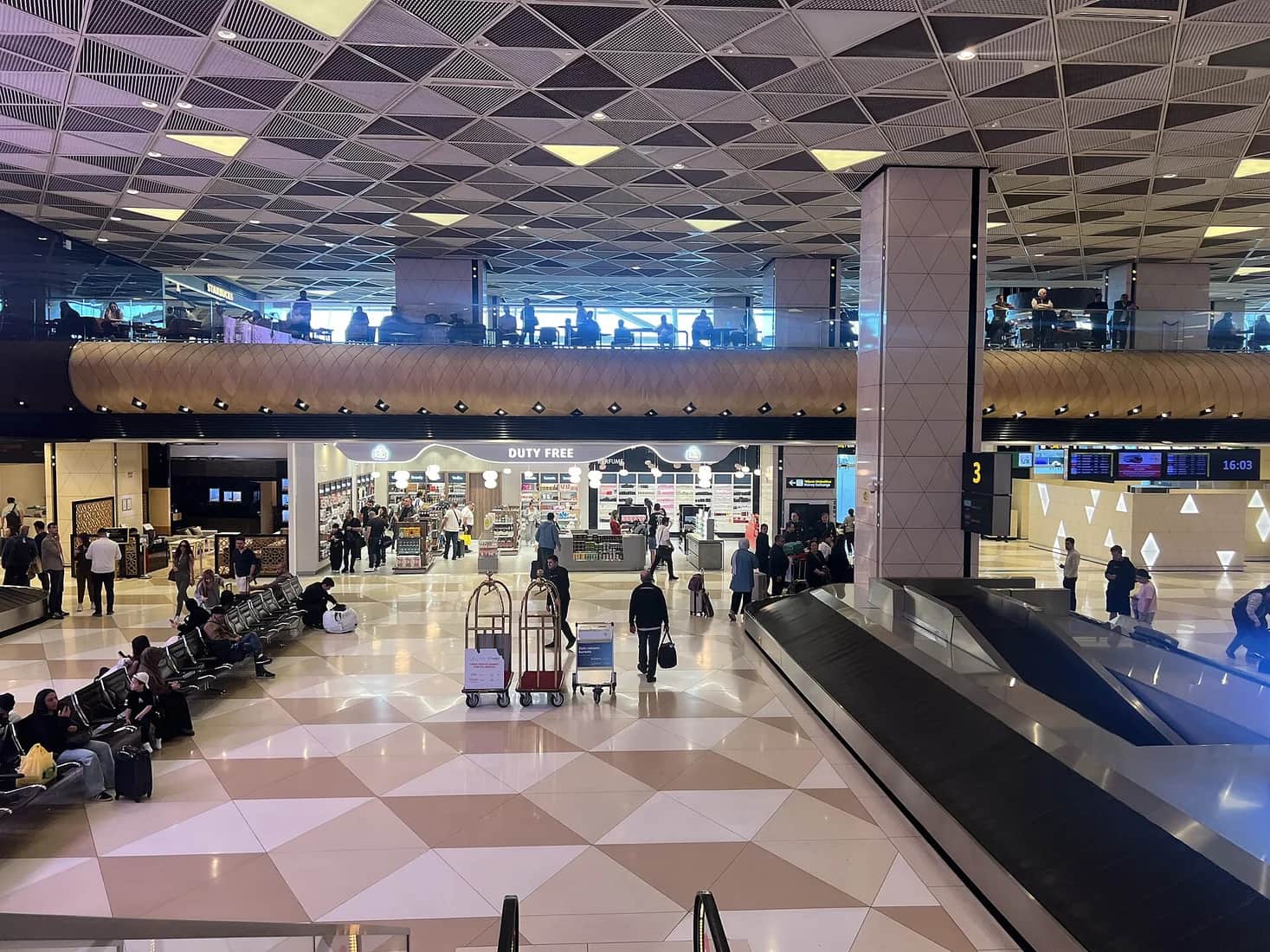 Travellers with luggage inside Baku International Airport terminal