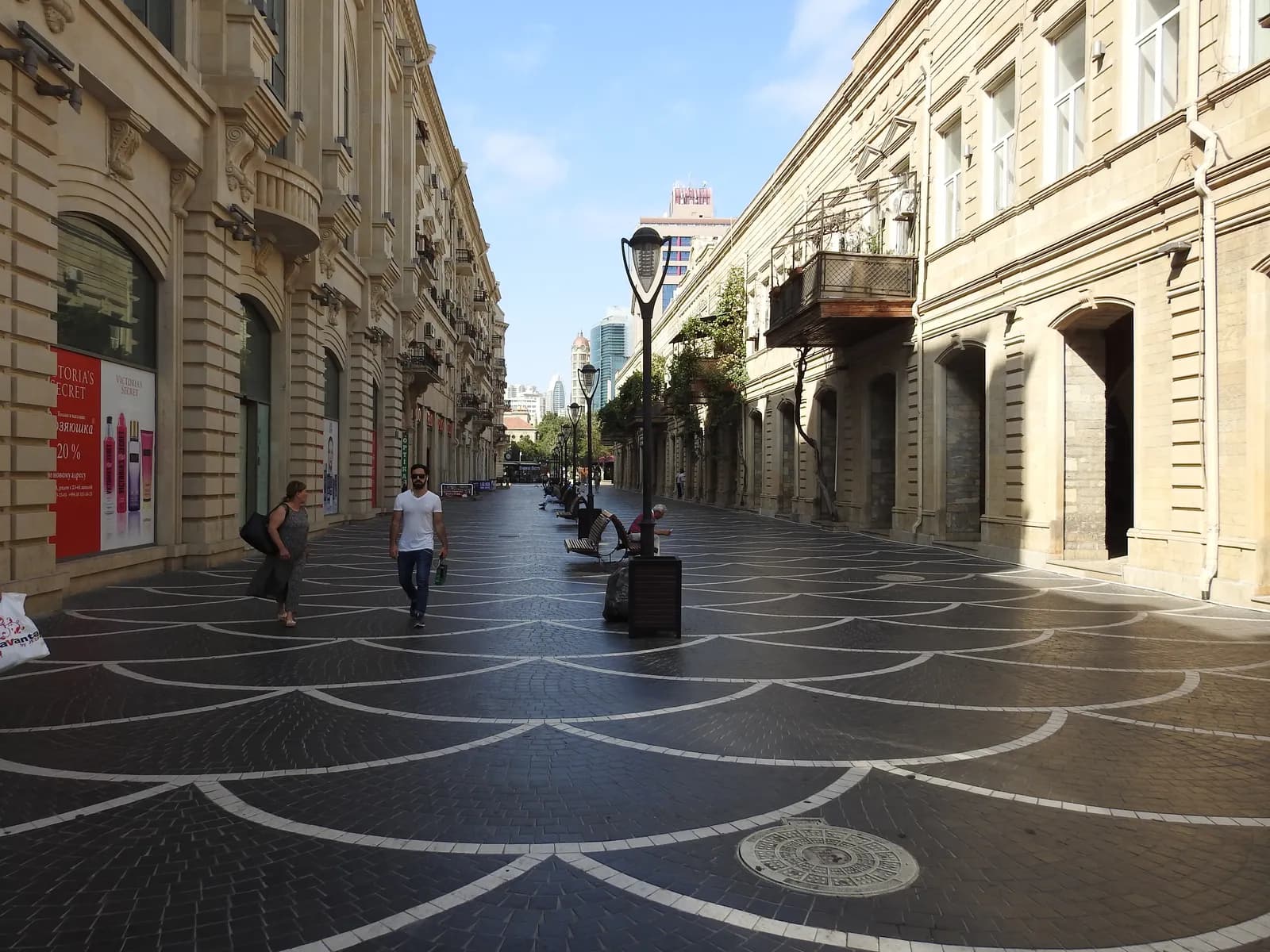 A few pedestrians on the paved, car-free stretch of Nizami Street in central Baku, shop fronts on both sides