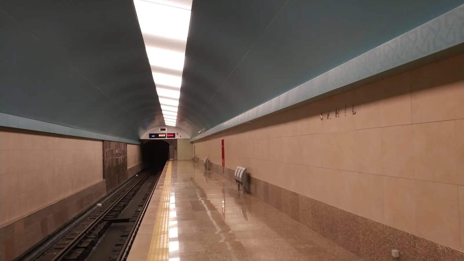 The platform hall of Sahil station on the Baku Metro after refurbishment, with the track on the left and the station name on the wall