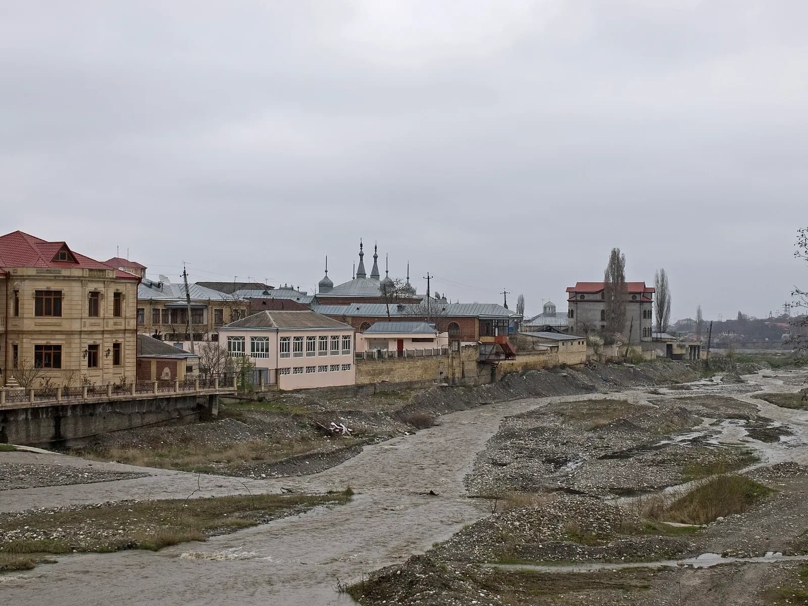 The braided bed of the Qudyal from the bridge, with Krasnaya Sloboda along the far bank and the synagogue domes above the roofline