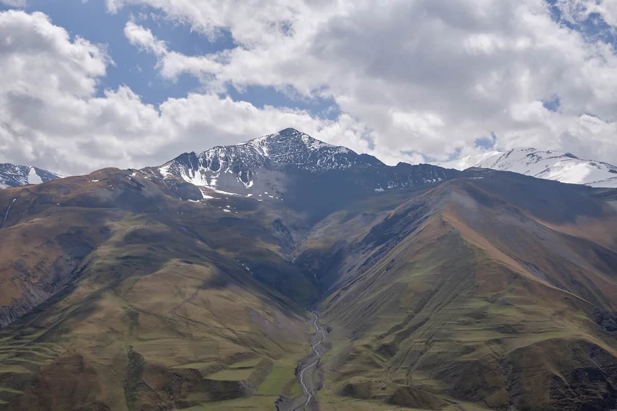 Snow-streaked mountain slopes and a river valley viewed from Khinalig in April 2023